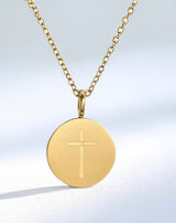 Gold necklace with a round pendant featuring a cross on a light gray background
