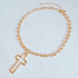 A gold cross pendant necklace on a U-shaped chain