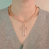 Woman wearing a gold cross necklace with a u-chain