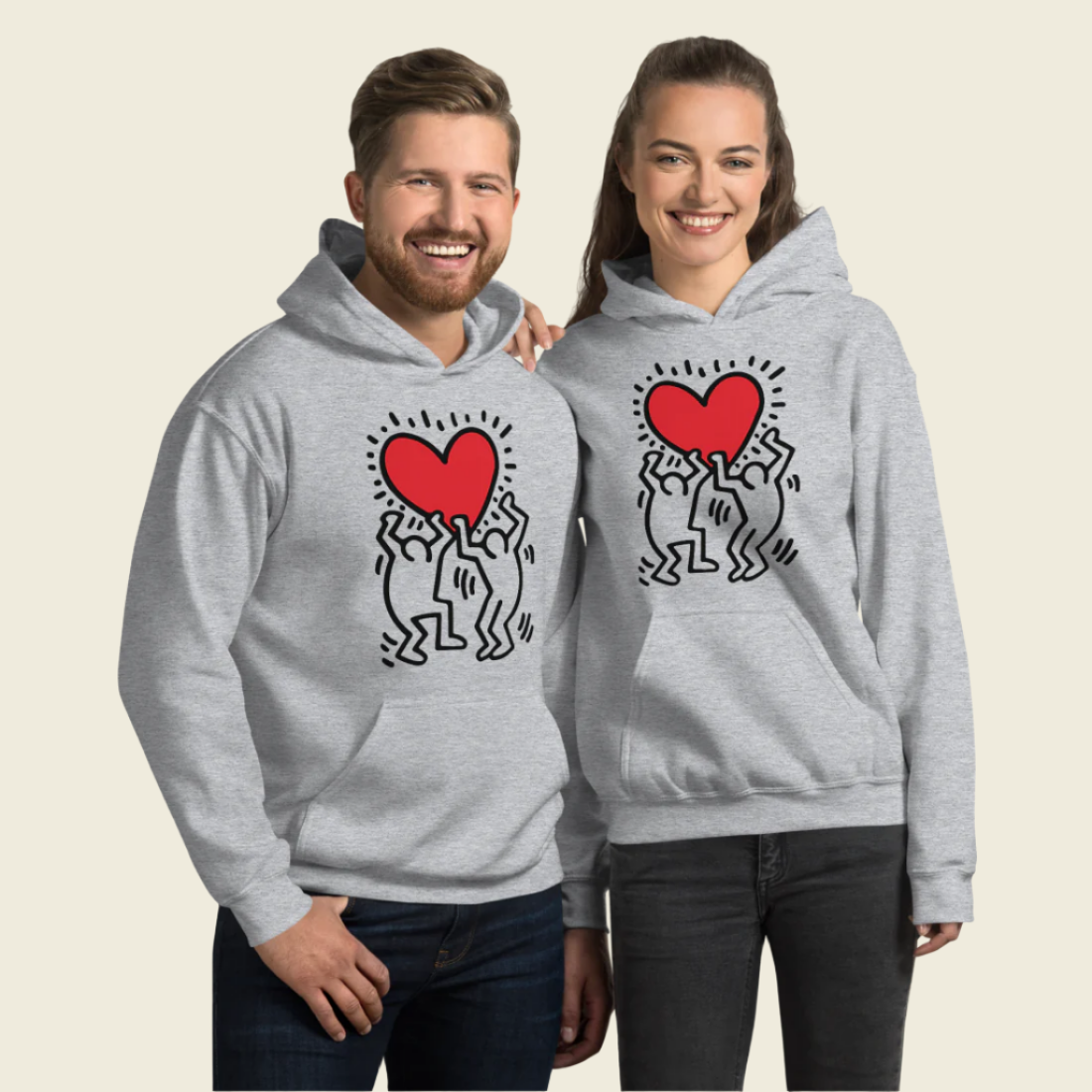 A man and woman wearing "Men Holding Heart Icon" hoodies, featuring a street art style graphic of a man holding a heart.